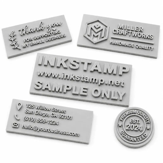 Collection of custom engraved rubber stamp dies with raised lettering and logo designs on a white background, showcasing different personalized rubber stamp engraving styles.